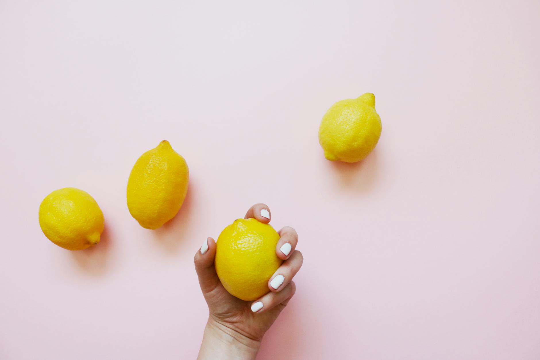 A hand holding a lemon clitoral vibrator against a minimalist purple backdrop, representing reclaimed pleasure