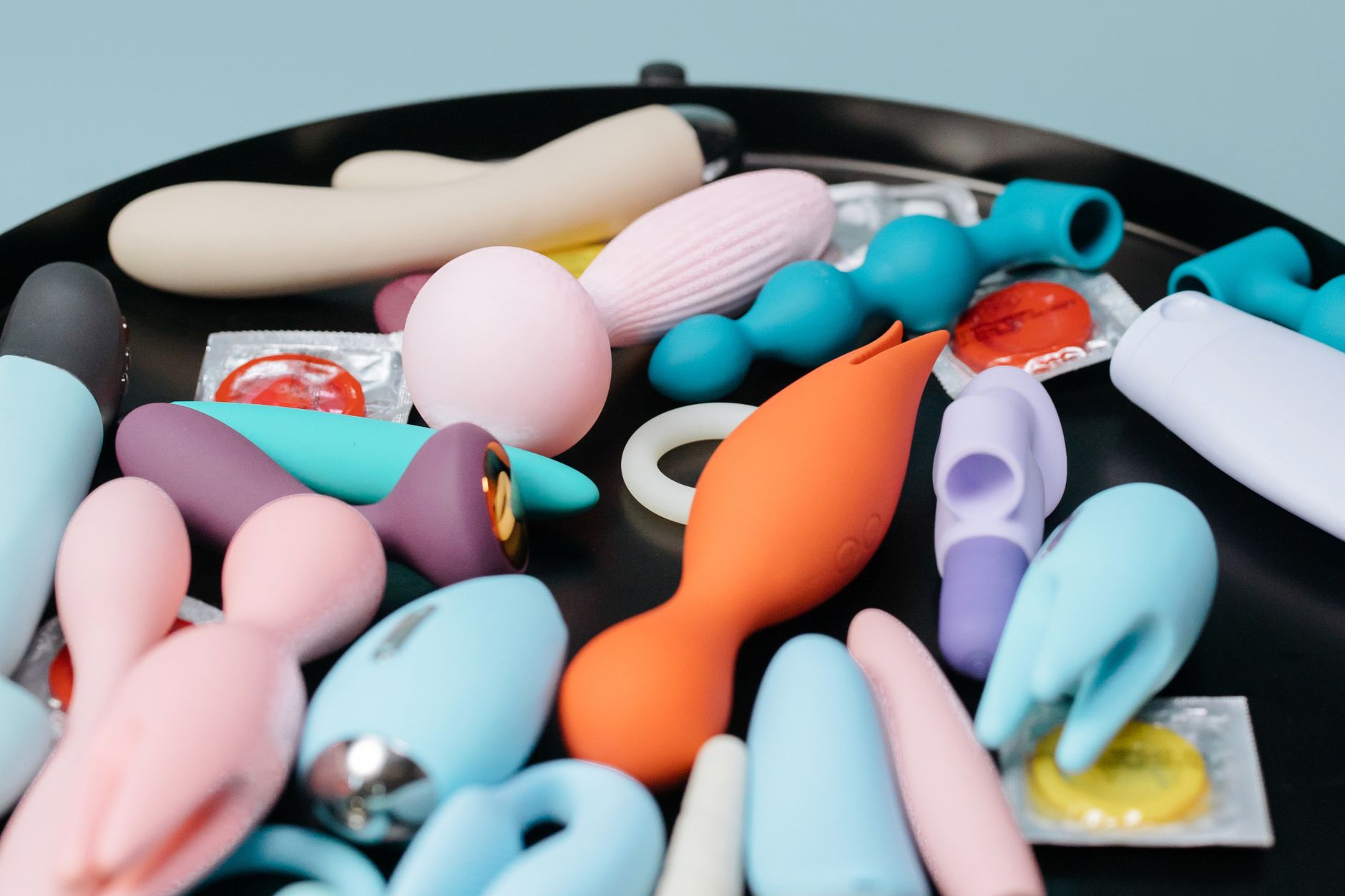 A collection of colorful vibrators and sex toys arranged on a black tray, showing diversity in design and shape.