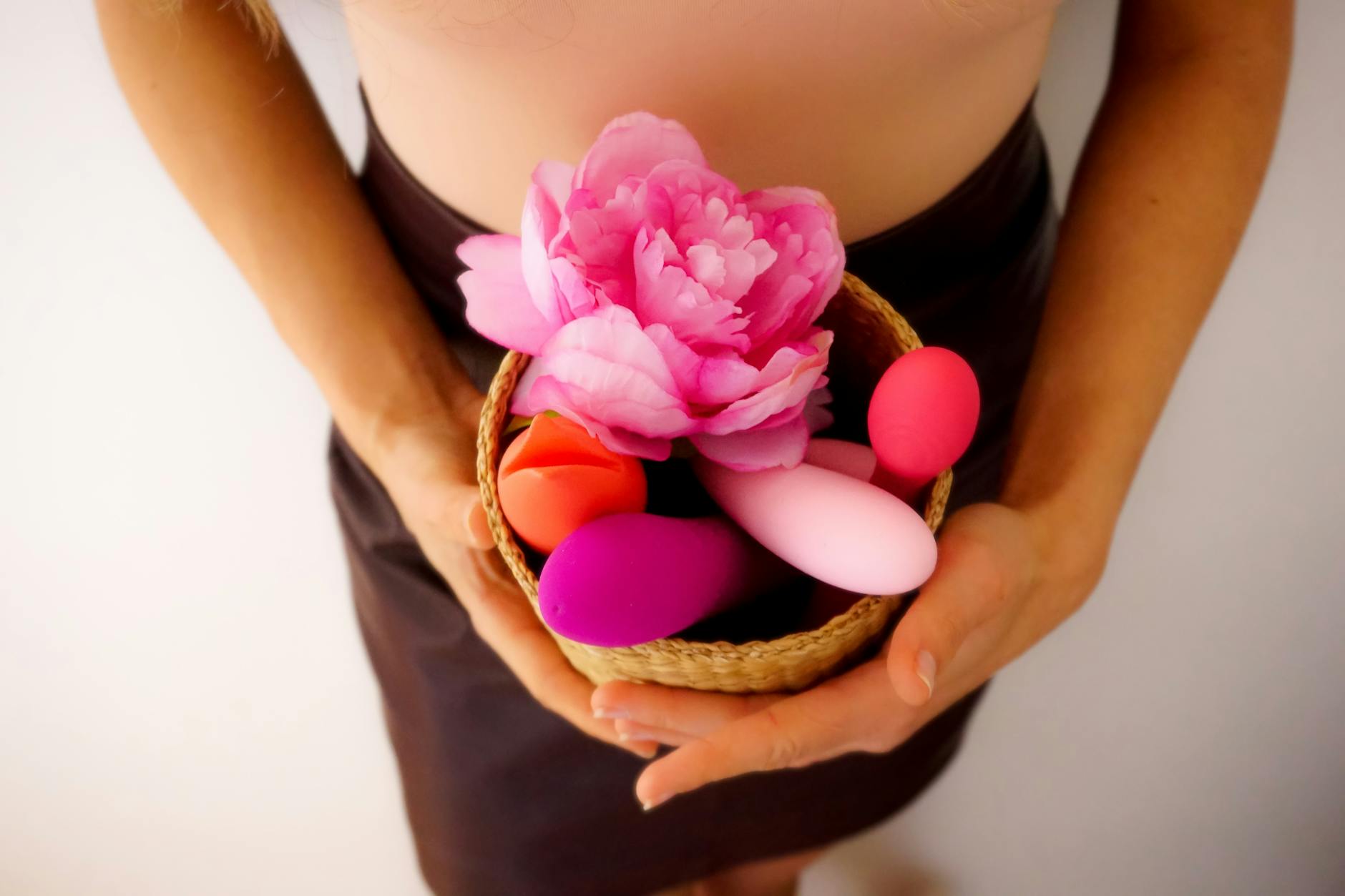 Woman holding two colorful vibrators against a purple background, representing choice and communication in intimate relationships